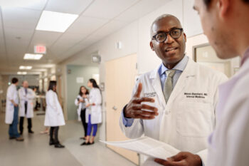 Melvin Blanchard, MD, talks with Andrew Young, MD, PhD, at the Center for Outpatient Health on the Washington University Medical Campus. Young, a recent graduate of the university’s Medical Scientist Training Program, recently started his residency training. Blanchard is the lead author on a study in which he advocates best practices for physician-scientist training programs. (Photo: Matt Miller/School of Medicine)